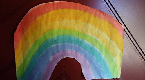 Ein selbstgemalter Regenbogen klebt an einer Haustür.