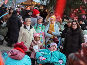 Viele Besucher auf Weihnachtsmarkt. Im Vordergrund ein Kind im Rollstuhl mit dicker Winterkleidung.