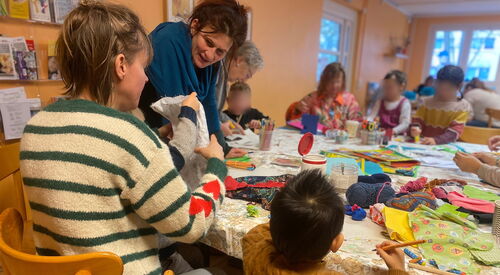 Kinder und Erwachsene an einem Tisch. Malen und basteln.