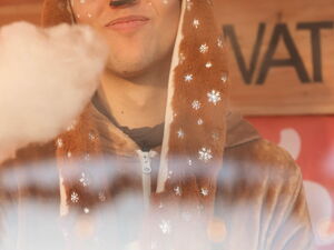 Person im Rentier-Kostüm macht Zuckerwatte.