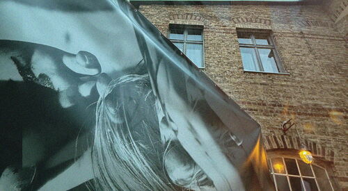 Schwarz-weißes-künstlerisches Banner vor groß wirkenden Gebäude. Frosch-Perspektive.