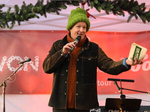 Mann mit dicker grünen Mütze und Mikrophon in der Hand moderiert.