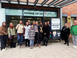 Gruppenbild: 13 Menschen vor dem Eingang zur Bundesagentur für Arbeit.