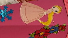 Pinke Schultüte mit Prinzessin auf einem Tisch, daneben Bastelvorlagen und Schere.