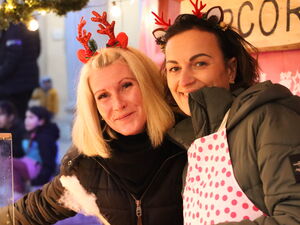 Im Popcornstand. Zwei Frauen die in die Kamera lächeln. Sie tragen kleine rote Geweihe auf dem Kopf und stehen eng beieinander.