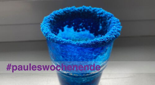 Ein Glas mit blauen Salzkristallen im inneren und am Rand oben.