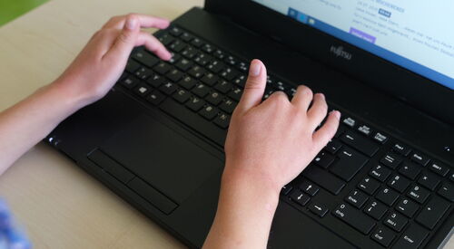 Kind arbeitet am Laptop