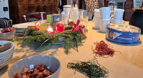 Tisch mit Tassen, Keksdose und Adventskranz.