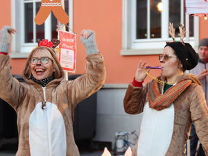 Zwei Frauen in Rentier-Kostümen. Eine jubelt mit erhobenen Armen, die andere bläst in eine Trillerpfeife.