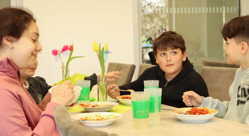 2 Mädchen, 2 Jungs am Tisch beim gemeinsamen Essen.