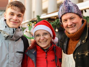 Ein Jugendlicher, eine Frau mit roter Weihnachtsmütze und ein Mann mit Mütze. Der Moderator steht rechts.