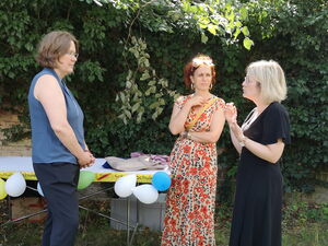 3 Frauen stehen auf der Wiese und unterhalten sich.