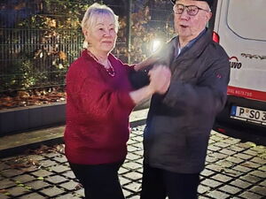 Älteres Tanz-Paar, tanzen draußen, es ist schon dunkel. Im Hintergrund ein weißer Transporter.