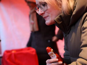 Ein blonde Grau mit Elchgeweih und Brille hält einen Schoko-Weihnachtsmann und hat ein parr Mandarinen vor sich.