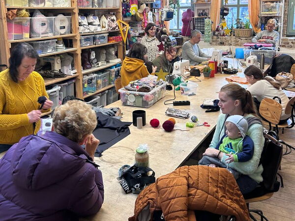 Mehrere Personen in einem großen Raum nähen.