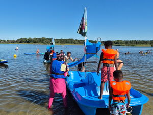 Blaues Spielboot mit Rutsche für kleine Kinder am Strand eines Sees. Kinder spielen.
