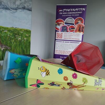 3 leere große Zuckertüten liegen auf einem Tisch. Dahinter ein großer lila Aufstelle. Text: AWO Spendenaktion für mehr Chancengleichheit.