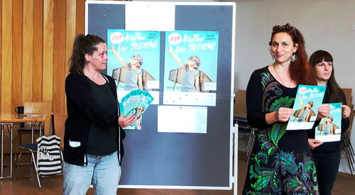 Fünf Personen mit Kultur für Jeden Flyer und Plakaten in den Händen. Dahinter ein Pinntafel an der zwei Plakate angepinnt sind.