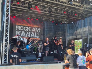 Frauen Band auf der Bühne. An der Bühne Plakate von Rock am Kanal.