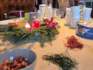Tisch mit Tassen, Keksdose und Adventskranz.