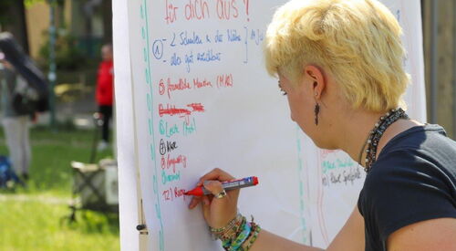 Blonde Frau schreibt mit rotem Stift an ein Flipchart.