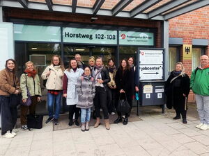 Gruppenbild: 13 Menschen vor dem Eingang zur Bundesagentur für Arbeit.