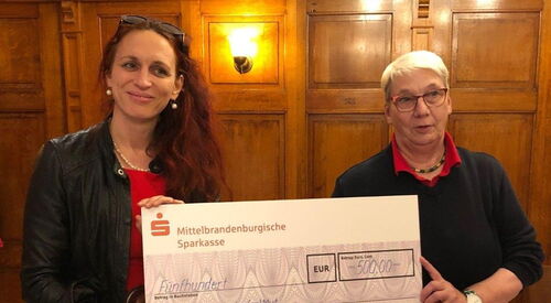 Zwei Frauen halten einen symbolische Scheck hoch