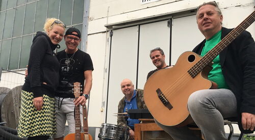 Eine Band mit Musikinstrumenten. Eine Frau und 4 Männer.