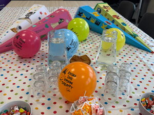 Auf einem Tisch: bunte Ballons, Zuckertüten, Süßigkeiten und Wasserkrüge.