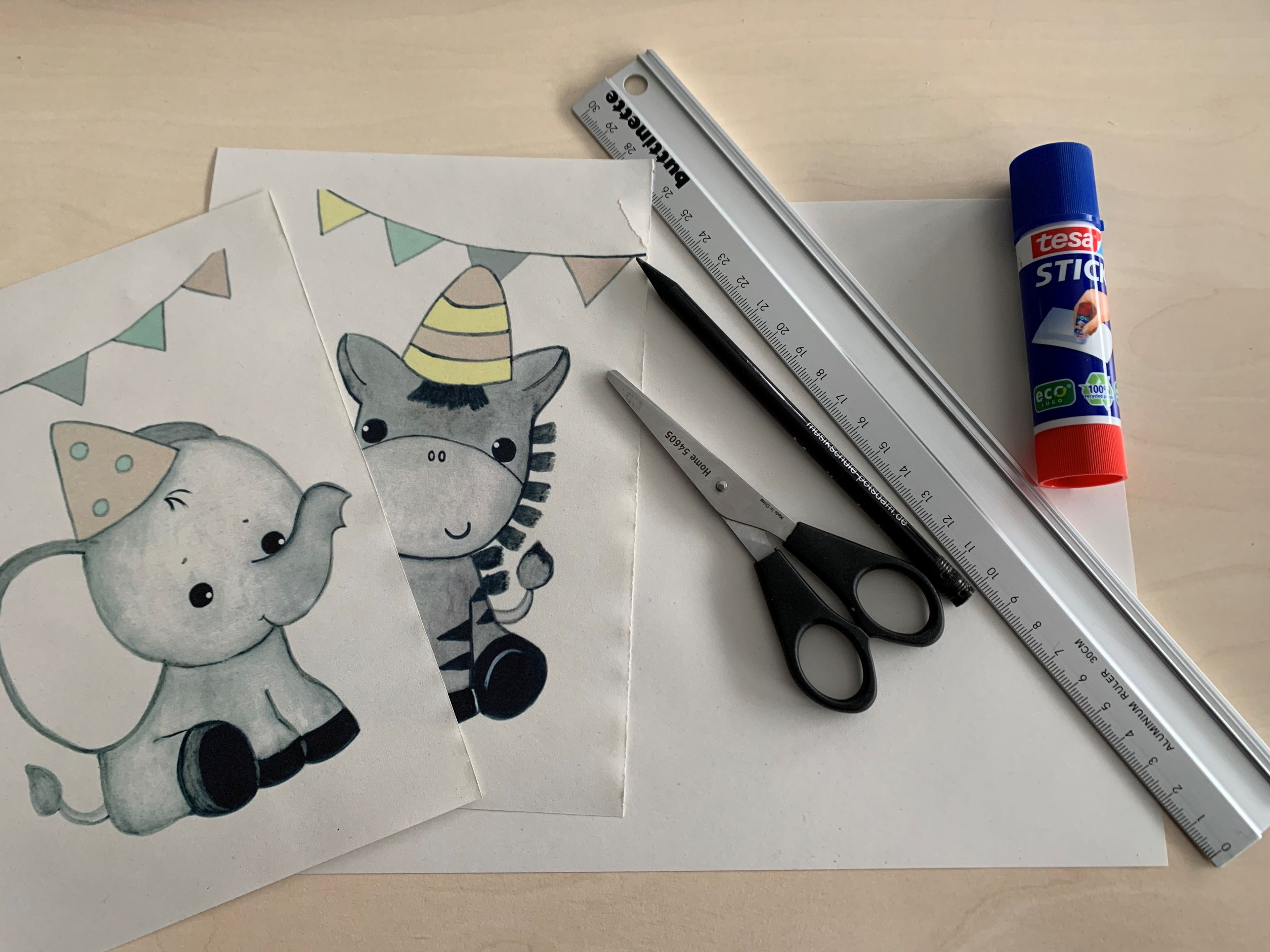 Papier mit Elefant und Zebra, dazu Schere, Stift, Lineal und ein Klebestick