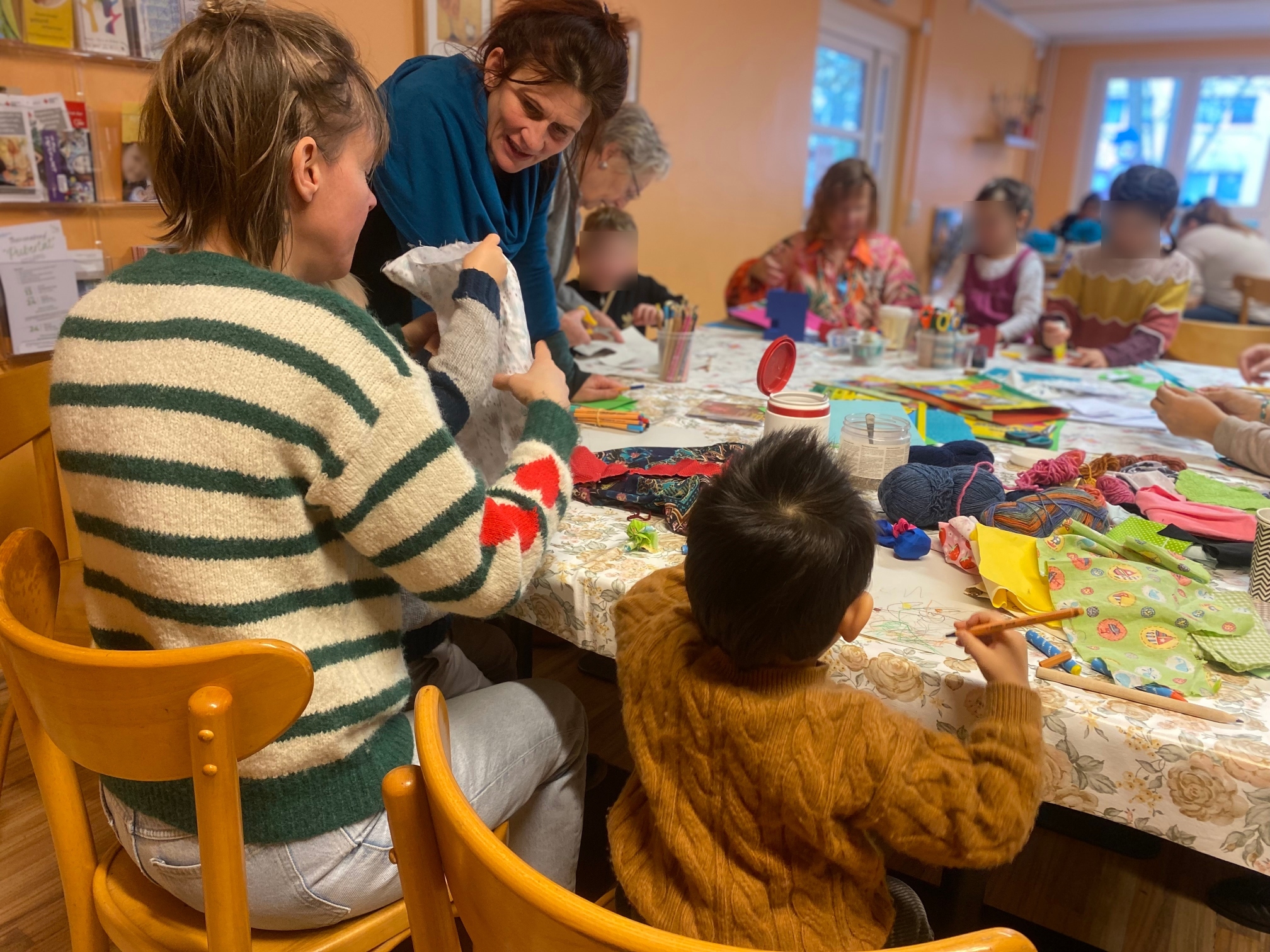 Kinder und Erwachsene an einem Tisch. Malen und basteln.