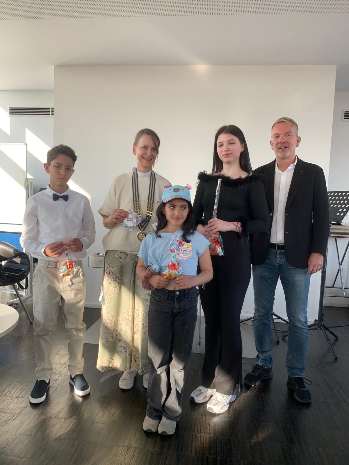 2 Erwachsene, 3 Kinder/Jugendliche. Sie stehen in einem hellen Raum und lächeln in die Kamera.