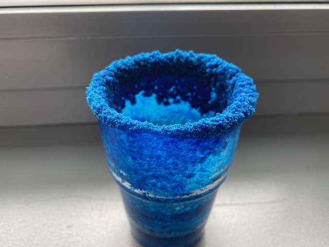 Ein Glas mit blau gefärbtem Salzkristallen